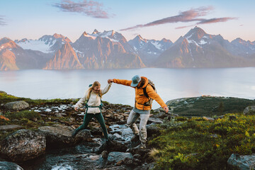 Wall Mural - couple hiking in norway man helps woman cross river in mountains healthy lifestyle outdoor active fa