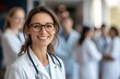 © Saad - A smiling female doctor stands in front of her team, surrounded by other doctors and nurses. Created with Ai