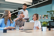 © ty - Four business professionals using laptop on desk discussing strategy company