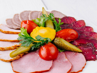 Wall Mural - Plate combining several types of meat cuts and pickles being served on white table