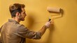 © Alexandr Peers - Home renovation: male painter applying yellow paint for professional interior design