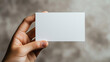 © Paul Peery - White Business Card Held by Hand Against Textured Grey Background