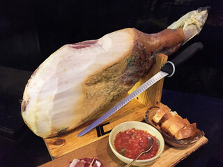 Deliciously presented cured ham on wooden board, accompanied by sauce and bread, perfect for gourmet meals.