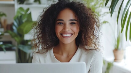 blasian female businesswoman working in a bright white office, smiling on a video call meeting with a client, demonstrating workplace success, creativity, and professional digital communication