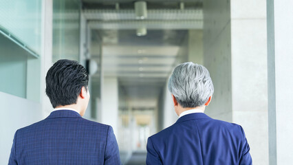 Fototapete - ビルの通路を歩く二人のビジネスパーソンの後ろ姿