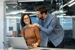 © Liubomir - Man and woman inside office at workplace, colleagues flirting and courting each other, businessman massaging colleague's shoulders.