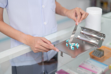 Wall Mural - Asian professional female pharmacist standing with arms crossed looking at camera charming smile pointing hand to pill bottle health care products in pharmacies Close-up and wide-angle shots