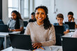 © Maskot - Portrait of smiling curly hair teenage girl sitting with laptop near desk in classroom at school