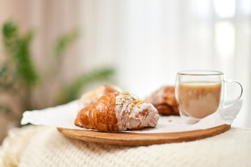 Delicious fresh french croissants and glass of coffee on wooden tray for breakfast in bed in the morning, tasty breakfast