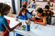 © Maskot - High angle view of female students painting on paper during art class in elementary school