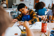 © Maskot - Boy doing finger painting on paper during art class at elementary school