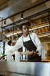 © Maskot - Low angle view of young chef holding salad bowl while working in commercial kitchen at restaurant