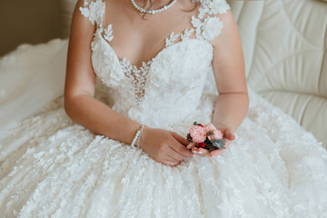 Wall Mural - A woman in a wedding dress is holding a pink flower in her hand. The dress is white and has lace detailing. The woman is sitting on a couch, and the flower is placed in her lap