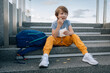 © Cavan Images - Little boy, with backpack, eats street food, French fries