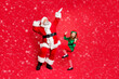 © deagreez - Full size photo of excited two people santa claus elf dancing enjoying midnight party wearing eyeglasses eyewear hat headwear spectacles isolated over red background