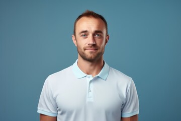 portrait of a satisfied man in his 30s wearing a sporty polo shirt in front of blank studio backdrop