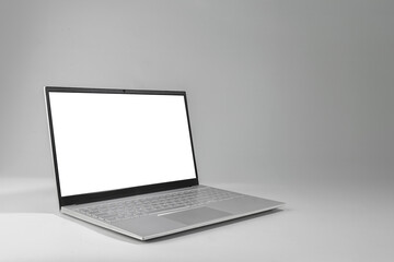 A laptop with a white screen sits on a grey surface