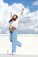 Joyful pregnant woman on the background of the sky. Concept of pregnancy.