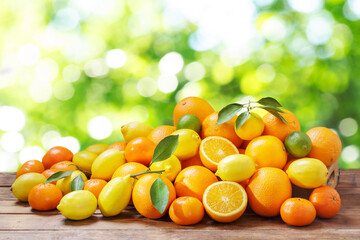 Mix of fresh citrus fruits with leaves on wooden table. Mandarin oranges fruit or tangerines, oranges, lemons and limes