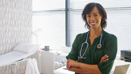 Wall Mural - Portrait Of Smiling Female Doctor With Stethoscope Standing By Desk In Office Or Surgery