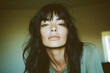 © yaqui_villegas - A woman with long dark hair and bangs poses indoors with a serene expression, accentuated by soft natural lighting creating a calm and reflective ambiance.