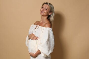 Wall Mural - Portrait of beautiful pregnant woman on beige background