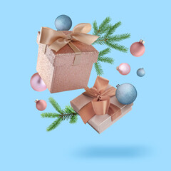 Wall Mural - Gift boxes, Christmas balls and fir tree branches in air on light blue background