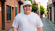 © QuoDesign - Plus size teenage boy wearing white t-shirt and white baseball cap standing in a city alley