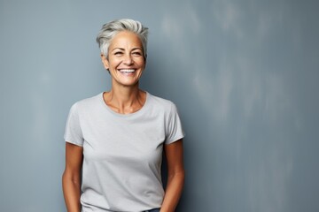 Wall Mural - Portrait of a happy woman in her 50s dressed in a casual t-shirt in plain cyclorama studio wall