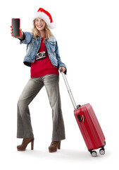 Wall Mural - festive Christmas holiday travel and vacation concept, tourist smiling woman in travel attire wearing a santa hat and showing smartphone screen, holding trolley suitcase, isolated on white background.