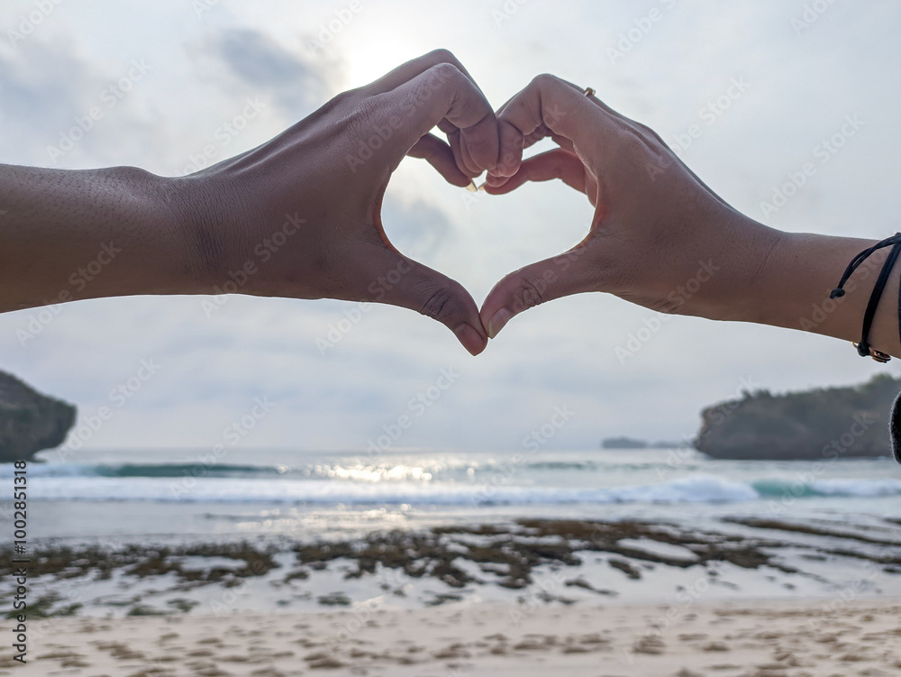 The couple shows their hands forming a heart symbolizing love and ...