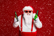 © deagreez - Portrait of his he attractive cheerful cheery funny fat white-haired Santa holding in hands beer bottles having fun isolated over bright vivid shine vibrant red burgundy maroon color background