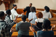 © Zamrznuti tonovi - Group of people raising their hands while praying inside the church
