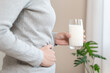 © Pormezz - asian young woman having a stomachache, abdominal pain or digestive, hand in holding belly after drink glass of milk. Lactose intolerance, allergy from dairy food, health care problem.