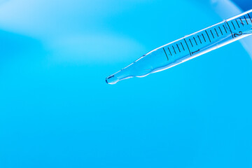 Beaker and water drop, science experiment,Test tubes with blue liquid water samples and pipette over blue background. Pipette dropping sample into test tube. Laboratory glassware, science laboratory