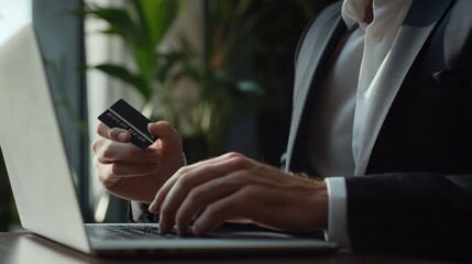 Poster - A man is typing on a laptop while holding a credit card