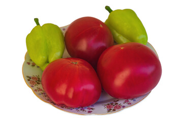 Three red ripe tomato fruits and two green bell peppers lie on a plate, isolated on a transparent white background. Harvesting for the concept of fertility and harvesting.