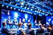 © sanjit536 - Business Conference Speaker Presenting to a Large Audience in a Professional Setting, on dark blue background