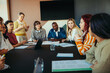 © Jacob Lund - Group of diverse classmates engaged in a collaborative learning discussion around a table in a modern classroom setting