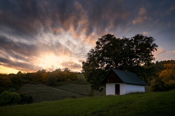 Autumn sunset landscape. Fall scenery with colored sky, trees and leafs. Country chalet near Banska Bystrica in central Slovakia