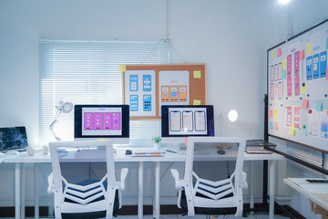 bright, modern office with no people, showing user interface designs on computer monitors and a whit