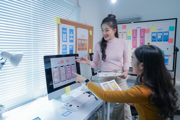 Two asian women working as ui/ux designers collaborating on a new project, developing wireframes for a mobile application