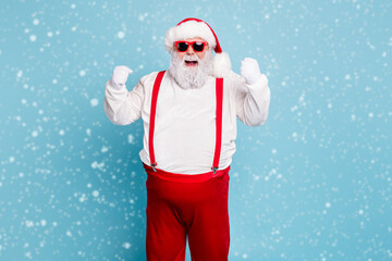 Wall Mural - Portrait of funny funky fat santa claus with big belly raise fists scream yeah have luck celebrate newyear x-mas party wear suspenders modern red spectacles isolated over blue color background