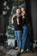 © Sofiia Shunkina - Cheerful Caucasian family with young parents and child celebrating Christmas by decorated tree. Joyful moments captured as father holds daughter playfully on shoulders.