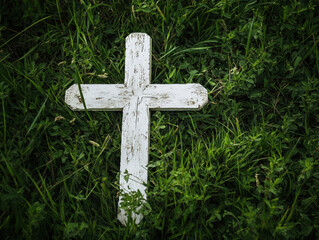 A weathered white cross nestled among lush green grass on a serene afternoon