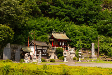 Beautiful shrine is located in Fujiyoshida Japan. The red wooden beams holding up the oriental slanted roof is quite typical of this architecture. Small white statues can be seen scattered around.