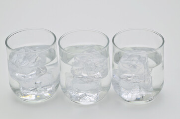 Three glasses of water with ice cubes, close up, isolated on white background