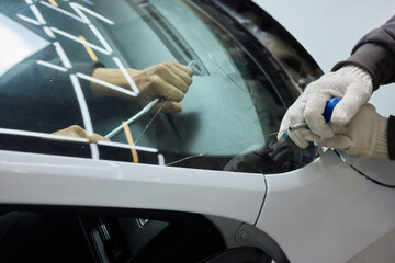 Automobile special workers remove old windscreen or windshield of a car in auto service station garage. Background