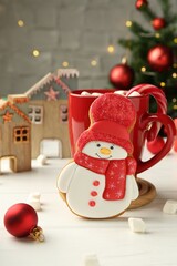 Poster - Delicious cookie in shape of snowman, cup with cocoa and Christmas decor on white wooden table