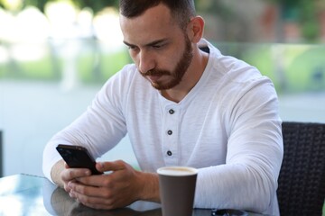 Poster - Handsome man with paper cup using smartphone at outdoor cafe